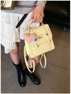 Detail of yellow polka dot backpack with a plush pink heart charm and metal buckle