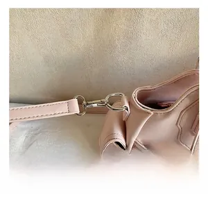 Detail of pink faux leather bag showing silver metal hook and side zipper pocket