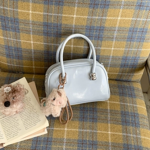 Sac à main en cuir verni bleu clair avec quincaillerie sphérique et breloque cochon rose
