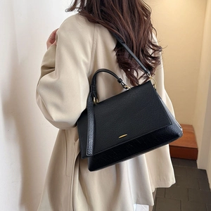 Détails d'un sac bandoulière en cuir gaufré noir avec ferrures dorées et rabat chic