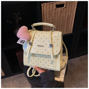 Detail of creamy yellow polka dot backpack with a cute pink heart plush pendant detail