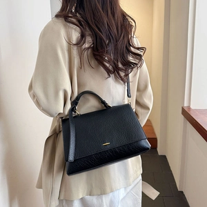 Détail du sac à main en cuir noir avec garniture dorée et bandoulière réglable
