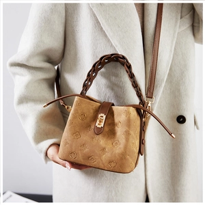 Detail of vintage embossed bucket bag with woven handle and metallic clasp on a model