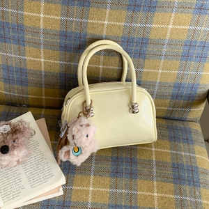 Détail du sac Boston crème avec boules argentées et charmant porte-clé alpaga rose