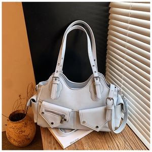Detail of light blue faux leather moto bag with silver hardware and utility pockets
