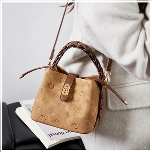 Detail of vintage embossed bucket bag with woven handle and gold metal lock buckle