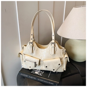 Detail of creamy white faux leather handbag featuring silver rivets and multi-pocket design