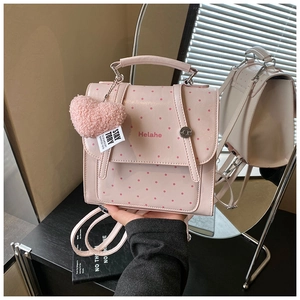 Detailed mirror view of a pink polka dot backpack with a heart charm and Helahe logo