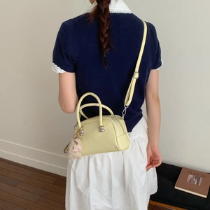 Détail du sac Boston jaune clair avec bandoulière réglable et breloque cochon rose