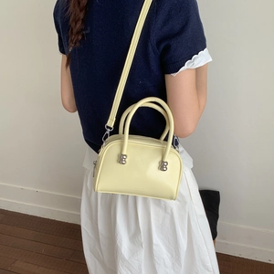 Détail du sac Boston en cuir jaune montrant la texture, les ferrures et la bandoulière