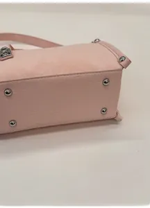 Detailed close-up of light pink leather bag base with four silver protective metal studs