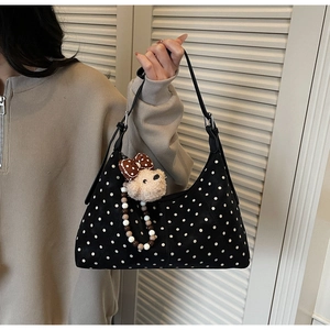 Detail of black polka dot crossbody bag featuring a cute plush bear charm with beads