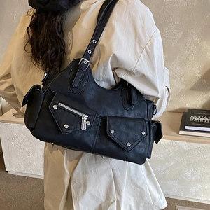 Detail of black faux leather motorcycle bag showing silver rivets and utility pockets