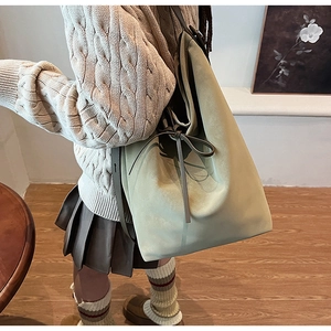Detail of vintage sage green suede bucket bag with drawstring bow and minimalist texture