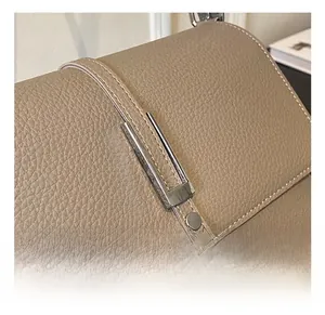 Close-up of silver metal buckle and stitching on lychee pattern leather shoulder bag
