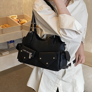 Close-up of matte black leather handbag with multiple pockets and metal rivet details