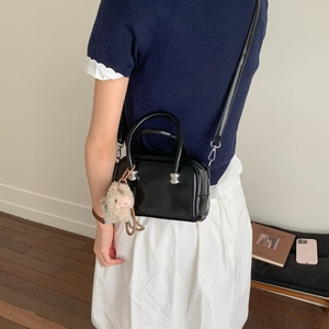 Détail d'un petit sac bandoulière noir brillant avec un pendentif alpaga en peluche