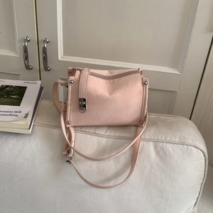 Close-up of light pink pillow bag with pleated texture and silver metal studs detail
