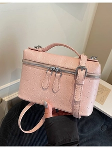 Pink ostrich pattern box handbag with silver zipper shown in a stylish hand-held pose