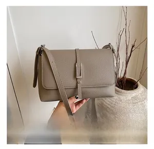 Detail shot of taupe square bag featuring pebbled leather texture and metal buckle