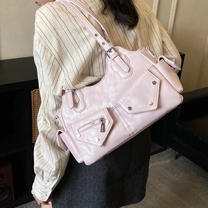 Detailed view of pink moto-style shoulder bag featuring silver zippers and rivets