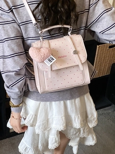 Pink polka dot leather backpack with heart charm and shoulder strap on model