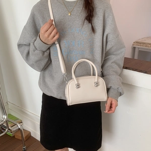 Détail du petit sac bandoulière blanc cassé avec boucles sphériques et bandoulière réglable