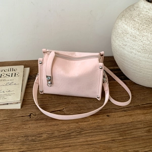 Detailed top view of a light pink pillow bag featuring silver studs and zipper closure