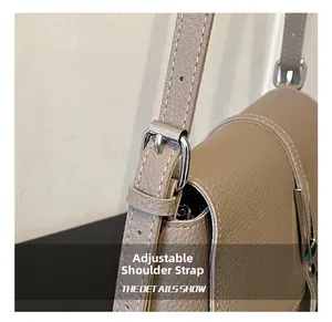 Close-up of adjustable strap buckle and silver hardware on a gray leather handbag