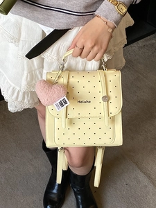 Fashionable light yellow polka dot backpack with a cute pink heart plush pendant