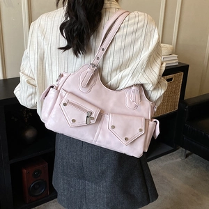Detail of pink moto-style shoulder bag featuring multi-pocket design and silver rivets