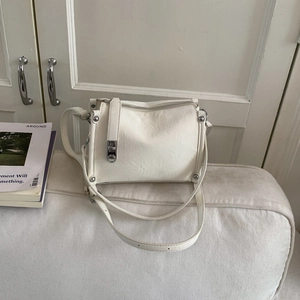 Detailed close-up of cream pillow bag featuring pleated leather texture and silver hardware