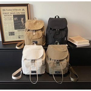 Detailed close-up of four canvas backpacks in khaki, black, cream, and olive green colors