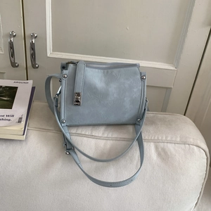 Detail of light blue pillow bag showing natural leather texture and silver hardware accents