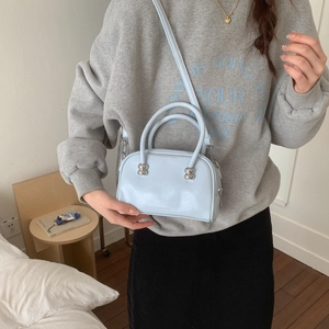Détail d'un sac polochon bleu clair avec finition brillante et perles métalliques