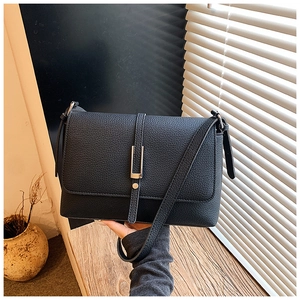 Detail of black lychee texture crossbody bag featuring elegant gold metallic buckle