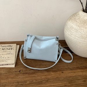 Detail of light blue pillow bag with soft leather texture and silver metal rivets