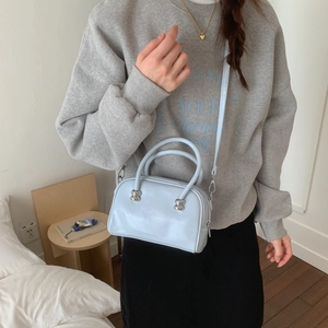 Détail du sac à main en cuir verni bleu clair avec des clous métalliques argentés au fond