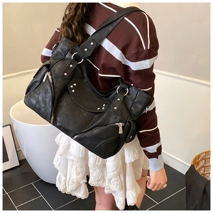 Détails d'un sac moto noir en cuir vintage avec rivets argentés portés par un mannequin