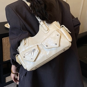 Detail of beige faux leather moto bag with silver rivets and multiple zip pockets