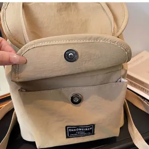 Close-up of khaki nylon backpack featuring magnetic snap closure and front pocket detail