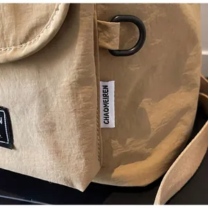 Detail of durable D-ring buckle and brand label on khaki nylon backpack fabric