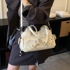 Close-up of cream motorcycle bag with multiple zippers and metallic rivet details