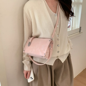 Detail of pink leather handbag featuring silver stud accents and metal lock closure
