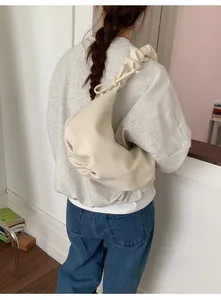 Detail der cremeweißen Dumpling-Tasche mit plissiertem Trageriemen und weicher Ledertextur