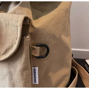 Detailed close-up of a durable matte black metal D-ring buckle on a khaki nylon backpack