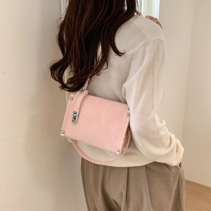 Detail of light pink crossbody bag with silver rivet trim and matte leather finish