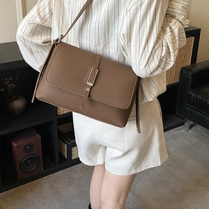 Detail view of brown textured leather crossbody bag with silver buckle and flap cover