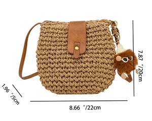 Detail view of woven straw crossbody bag with leather flap and 22x20x5cm dimensions
