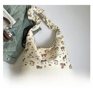 Close-up of beige canvas tote with colorful rocking horse print and pleated shoulder strap